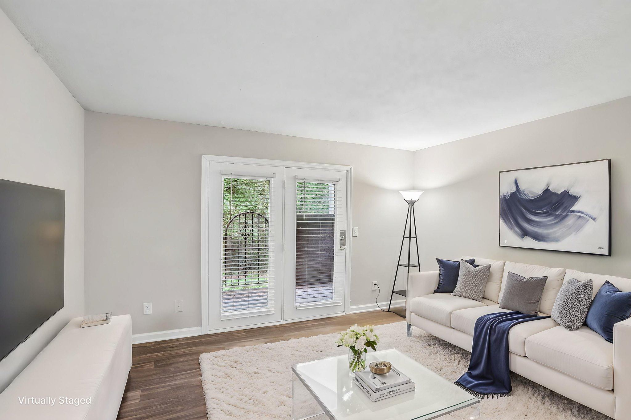 A living room with a white couch, a coffee table, and a painting on the wall.